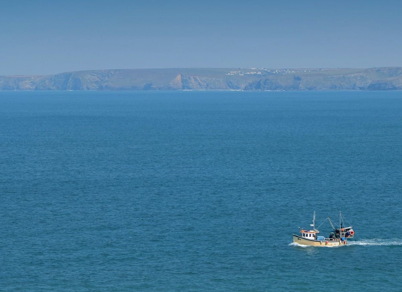 Fishing boat departing into pristine water to catch wild seafood.