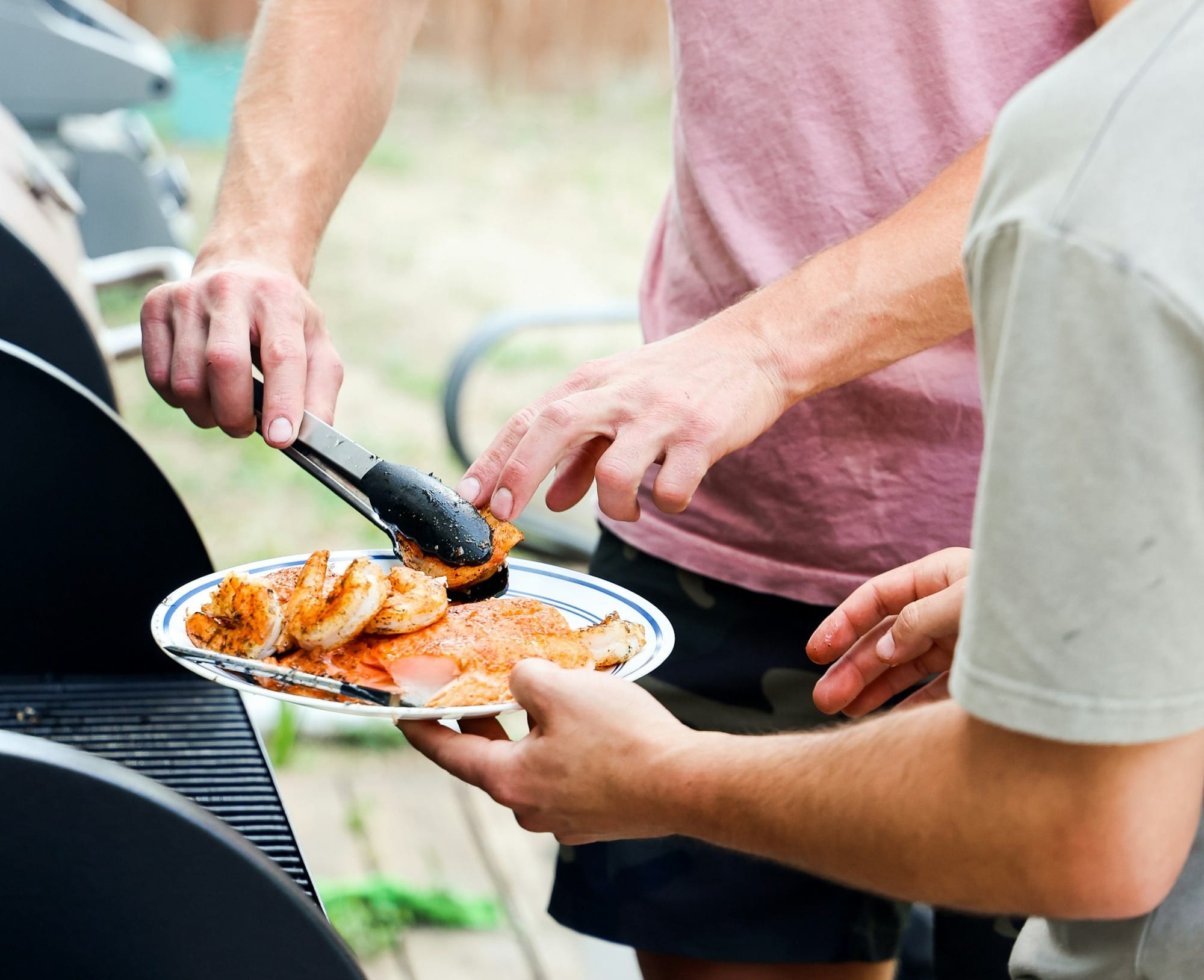 A man serving shrimp and salmon from a grill