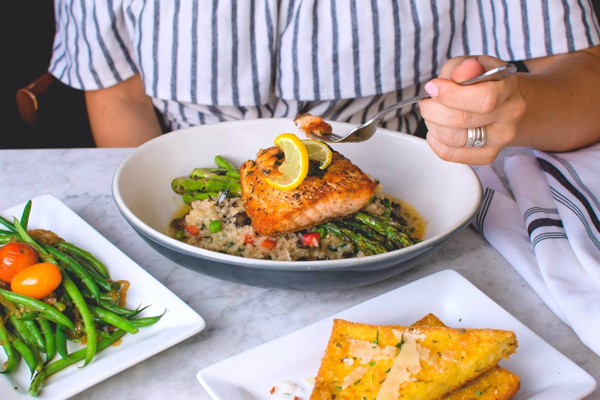 Woman eating grilled salmon for dinner