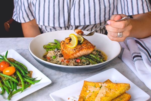 Woman eating grilled salmon for dinner