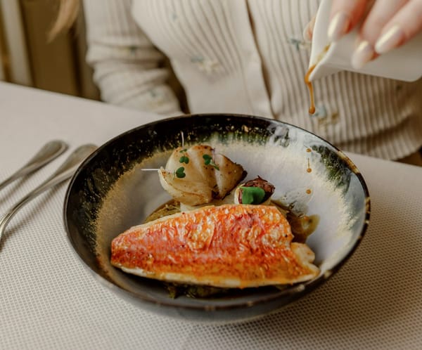 woman pouring sauce over baked snapper